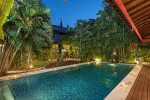 a swimming pool in a backyard with palm trees at Villa Kaja by Nagisa Bali in Seminyak