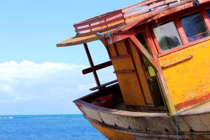 un viejo barco de madera sentado en el agua en Pousada Badejo en Japaratinga