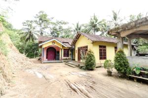 a yellow house with a red door on a dirt road at Kasmiyem Homestay in Sermo