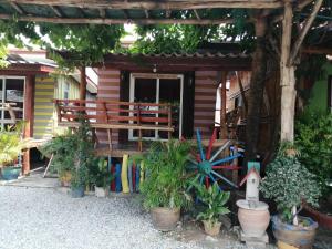 une maison avec un banc et des plantes devant elle dans l'établissement Nang Phraya Resort, à Ban Khok Mai Den (1)