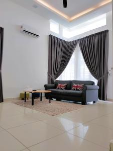 uma sala de estar com um sofá e uma mesa em A&H 81 HOMESTAY ALOR SETAR em Alor Setar