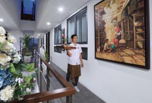 a man standing in a hallway with a painting on the wall at S7 SUITES GANDARIA in Jakarta