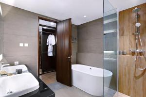 un bagno con vasca, lavandino e doccia di S7 SUITES GANDARIA a Giacarta