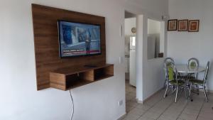 a living room with a tv and a table with chairs at 500M DA PRAIA, Prédio cm Piscina, 1Garagem, WI-FI 300 Mbps, Centro de Guarujá, próximo à Praia e Comércio, horários check-in e check-out flexíveis, churrasqueira, in Guarujá +38 photos