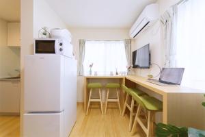 a kitchen with a refrigerator and a desk with a laptop at nestay villa tokyo otsuka in Tokyo