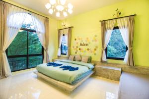 a bedroom with a bed in a room with windows at The Harmony Resort in Suan Phung