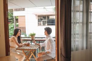 a man and woman sitting at a table on a balcony at Stay North Gate Bed and Breakfast in Chiang Mai
