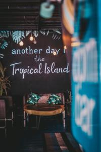 a sign that says another day the tropical island on a wall at DPM Koh Tao Diving Hotel & Bar in Ko Tao