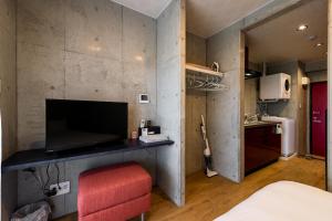 um pequeno quarto com uma cadeira vermelha e uma cozinha em Hotel Little Island Okinawa Matsuyama em Naha