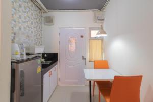 a kitchen with a white door and a table with orange chairs at Baansuanprannok Hotel in Bangkok