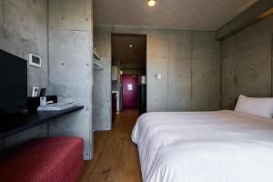 um quarto com uma cama branca e um sofá vermelho em Hotel Little Island Okinawa Matsuyama em Naha