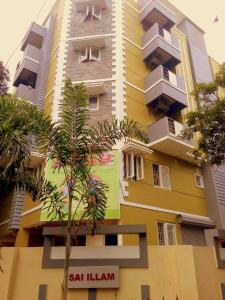 a tall building with a palm tree in front of it at Phoenix Serviced Apartment - Sai Illam in Chennai