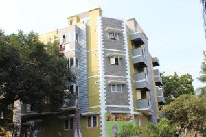 a tall yellow and white building with trees in front of it at Phoenix Serviced Apartment - Sai Illam in Chennai