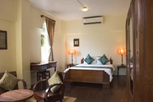 - une chambre avec un lit, une table et des chaises dans l'établissement La Villa, à Battambang