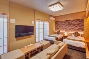 a hotel room with two beds and a couch at Hotel Amaterrace Nippombashi-higashi in Osaka