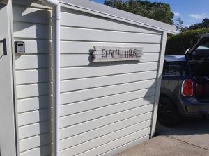 a garage door with a sign that reads devil likes at Stanmore Bay Beach House in Whangaparaoa