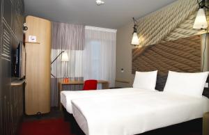 um quarto de hotel com uma cama grande e uma cadeira vermelha em ibis Tbilisi Stadium em Tbilisi