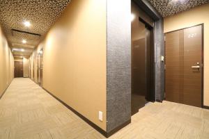 a corridor of a building with a door and wooden floors at Tokyo Tourist Inn in Tokyo