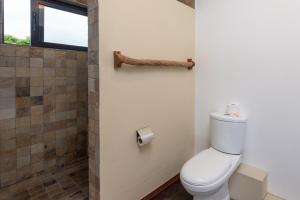 a bathroom with a toilet and a shower at Happy Days Guest House in Le Morne