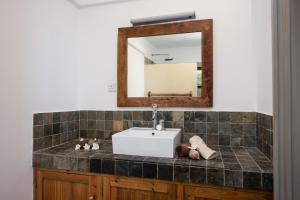 a bathroom with a sink and a mirror at Happy Days Guest House in Le Morne