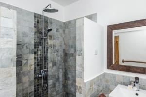 a bathroom with a shower with a sink and a mirror at Happy Days Guest House in Le Morne