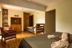 a room with a bedroom with a bed and a chair at Happy Days Guest House in Le Morne