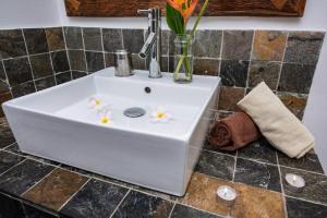 a white sink with flowers on it in a bathroom at Happy Days Guest House in Le Morne