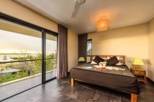 a bedroom with a bed with a teddy bear on it at Happy Days Guest House in Le Morne