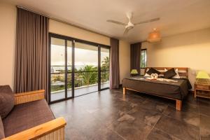 a bedroom with a bed and a balcony at Happy Days Guest House in Le Morne