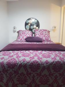 Una cama con una manta púrpura y almohadas. en Appart Madame à Chatelaillon plage 2 pers, en Châtelaillon-Plage