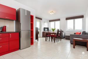 een keuken met rode kasten en een woonkamer bij Jantar Apartamenty- Zielone Tarasy in Kołobrzeg