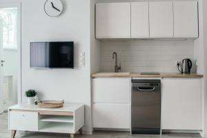 a kitchen with white cabinets and a sink and a dishwasher at Hello Apartments RAI Rajska in Gdańsk