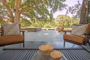 a patio with two chairs and a table and trees at Abelana River Lodge in Phalaborwa
