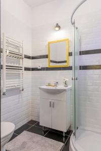a white bathroom with a sink and a mirror at CHÂTEAU: Upscale Suites in Bucharest's Historical Center! in Bucharest