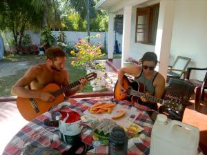 un hombre y una mujer tocando guitarras en una mesa en Ocean edge villa, en Midigama East