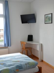 a bedroom with a bed and a desk and a television at Hotel Restaurant Bahnhof in Schüpfen