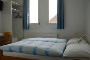 a bed in a bedroom with two windows at Hotel Restaurant Bahnhof in Schüpfen