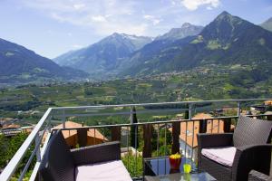 een balkon met stoelen en uitzicht op een vallei bij Schenna Garni Eden Bed & Breakfast in Schenna