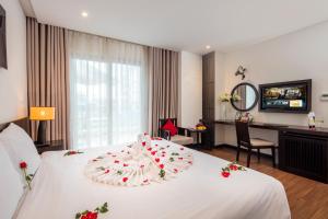 a hotel room with a white bed with flowers on it at Edele Hotel Nha Trang Beach in Nha Trang