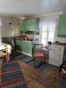 a kitchen with green cabinets and a table and a chair at Huset Alvina in Korsnäs +11 photos