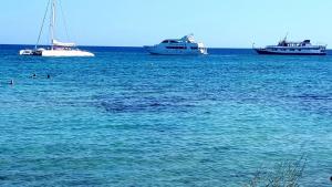 three boats in the ocean with people in the water at Karousos Beach Rooms in Ayia Napa