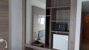 a mirror in a room with a bed and a microwave at Karousos Beach Rooms in Ayia Napa