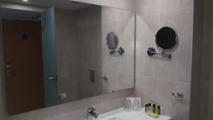 a bathroom with a sink and a large mirror at Karousos Beach Rooms in Ayia Napa +23 photos