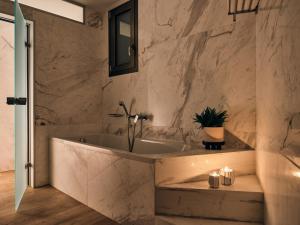 een badkamer met een bad en marmeren muren bij The Royal Blue a Luxury Beach Resort in Panormos Rethymno