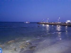 a beach with a boat in the ocean at night at Karousos Beach Rooms in Ayia Napa