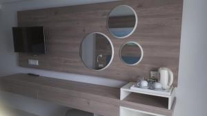 a bathroom with three mirrors on a wall with a tv at Karousos Beach Rooms in Ayia Napa
