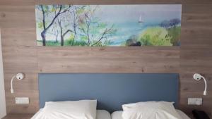 a painting above a bed with two white pillows at Karousos Beach Rooms in Ayia Napa