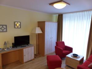 a living room with a television and red chairs at Ferienwohnung Seewald in Ostseebad Sellin