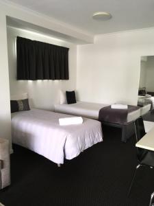a hotel room with two beds and a desk at Cooroy Luxury Motel Apartments in Cooroy
