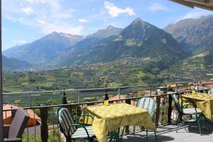 een tafel en stoelen op een balkon met uitzicht op een vallei bij Schenna Garni Eden Bed & Breakfast in Schenna